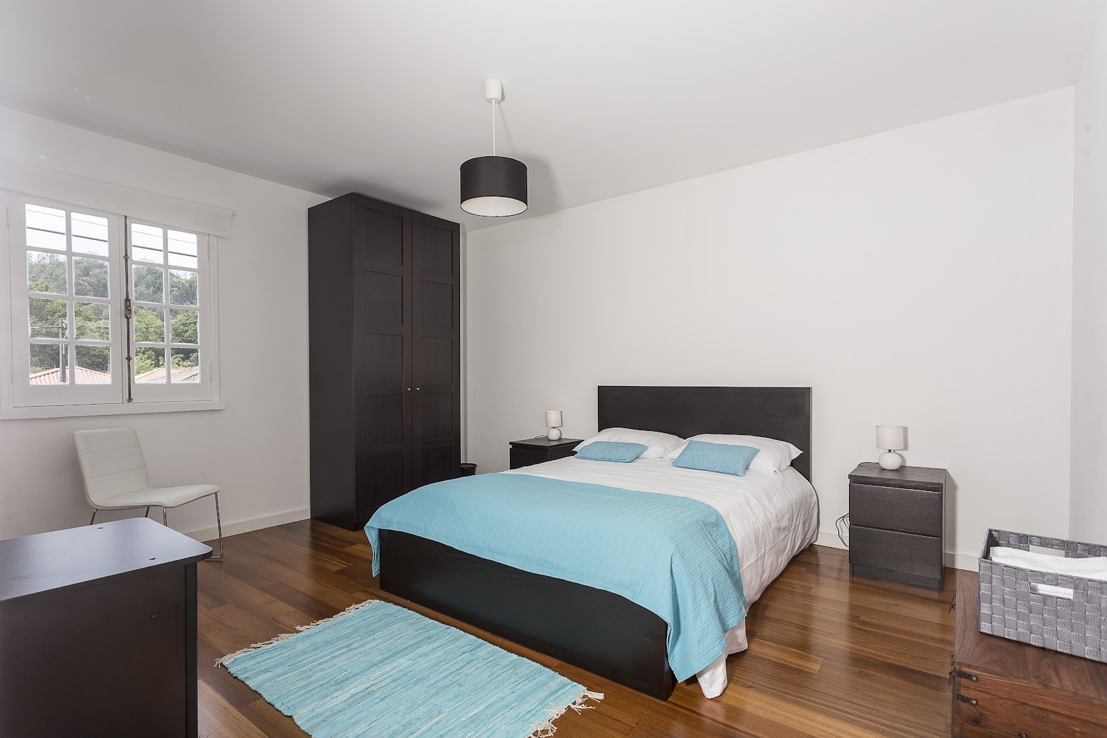 Bedroom with double bed, wooden floor, white walls, and window light